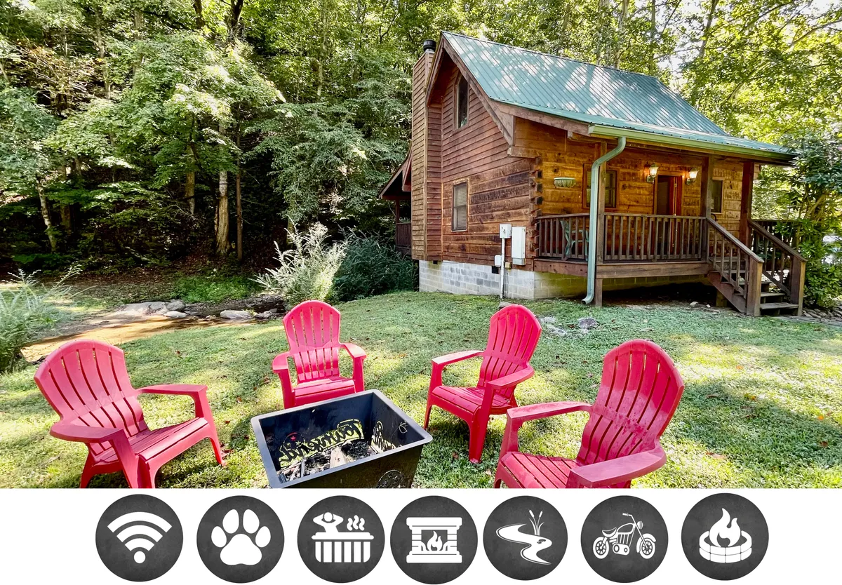 This exterior image showcases a charming wooden cabin nestled amid lush greenery, with inviting red Adirondack chairs arranged around a fire pit, creating an intimate space for guests to gather. The scene evokes warmth and relaxation, highlighting the cozy communal areas perfect for enjoying nature and spending quality time together.